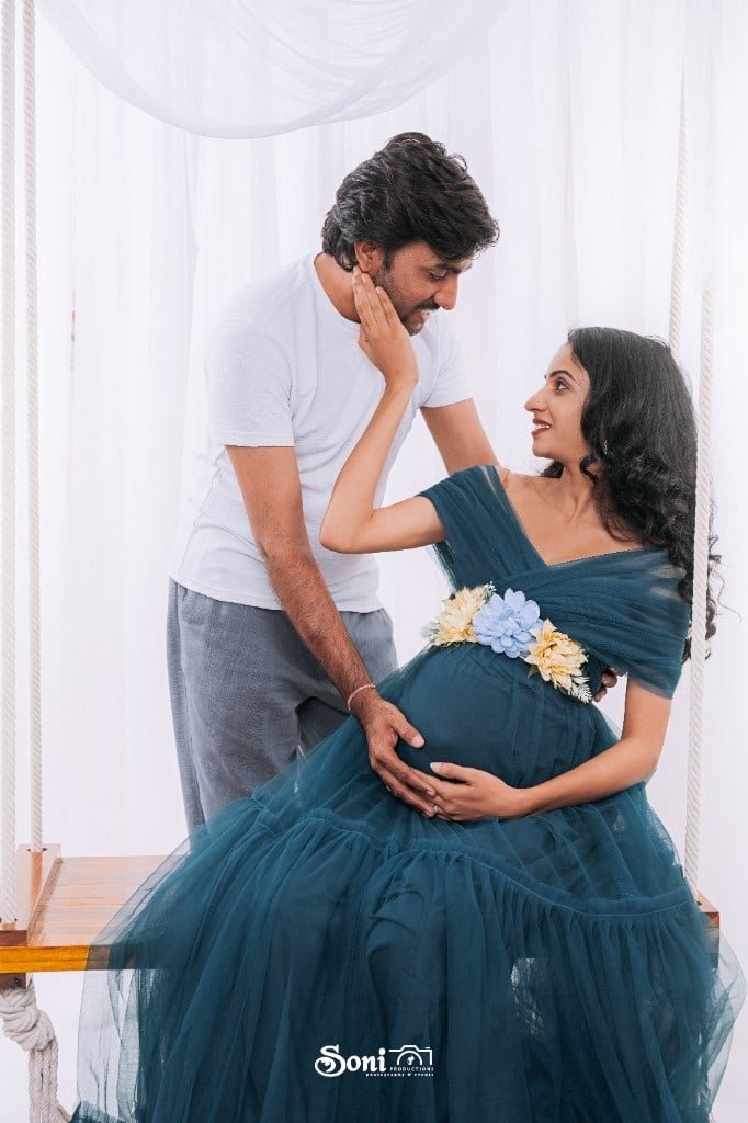 Maternity couple on a wooden swing