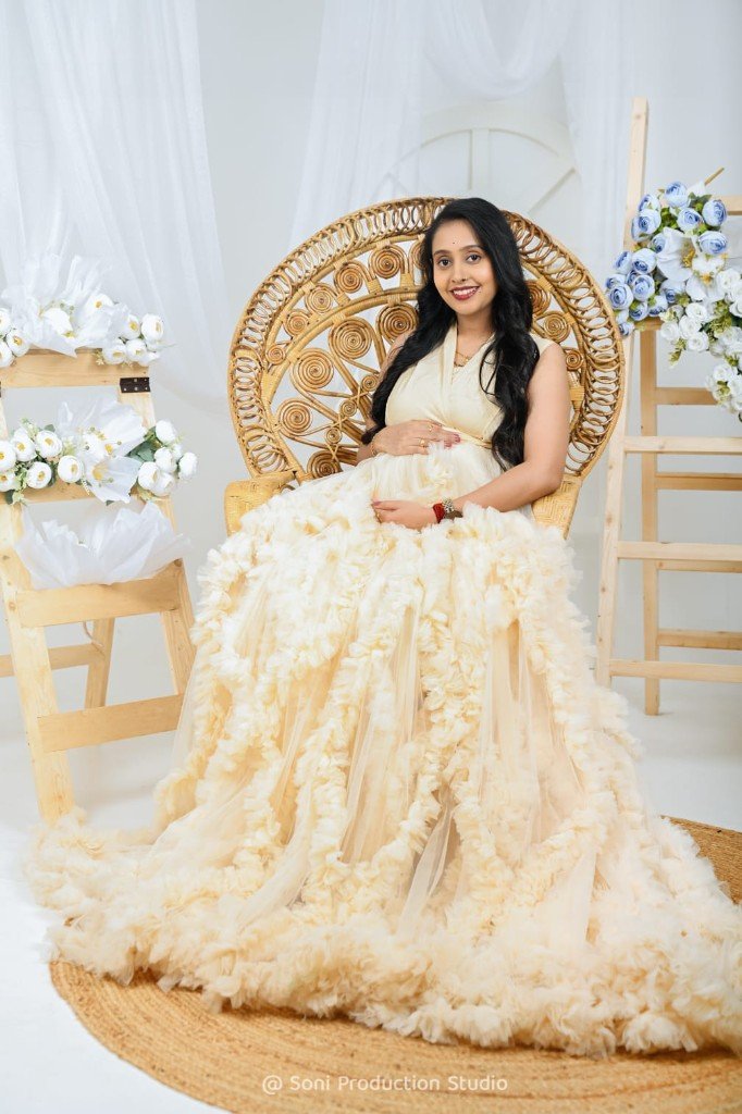 Maternity portrait in a cream gown with floral studio props