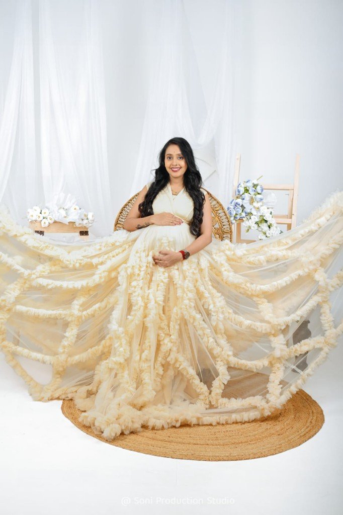 Maternity portrait in a cream ruffled gown — peacock chair