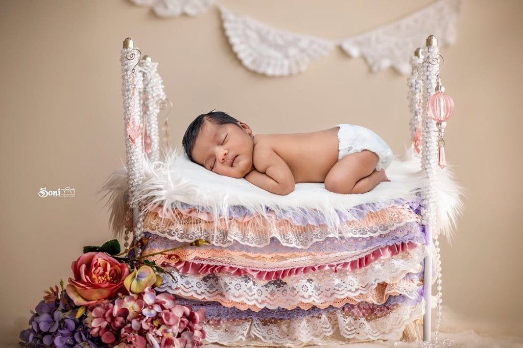Sleeping newborn on a lace and pearl bed