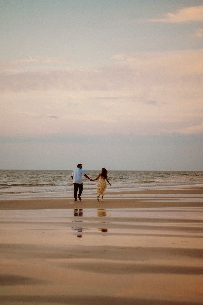 Couple walking the shore at golden hour