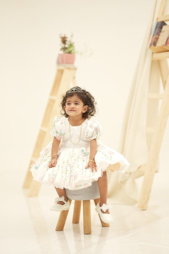 Toddler studio portrait in a floral dress and tiara